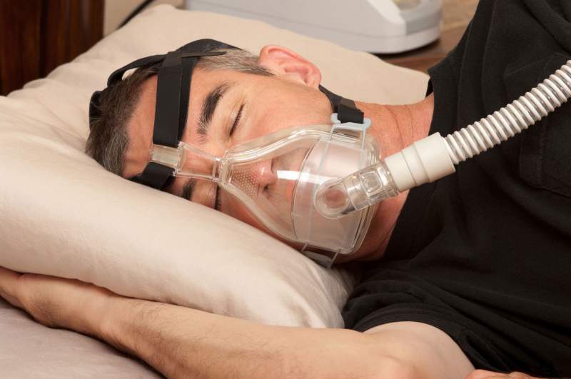 Man sleeping with his CPAP machine attached